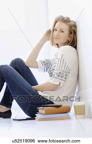 Stock Photograph - Portrait of young woman sitting on floor. Fotosearch