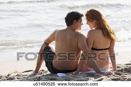 Stock Photograph - Rear view of couple on beach. Fotosearch