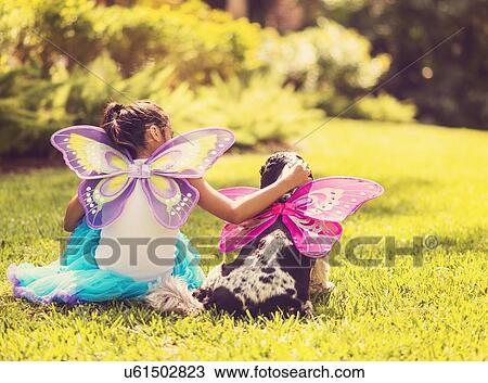 Rear view of girl (8-9) wearing fairy costume stroking dog View Large Photo Image Stock Image - Rear view of girl (8-9) wearing fairy costume stroking dog. Fotosearch