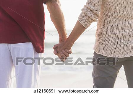Rear view of senior couple holding hands View Large Photo Image Stock Image - Rear view of senior couple holding hands. Fotosearch