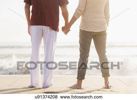 Rear view of senior couple holding hands View Large Photo Image Stock Photo - Rear view of senior couple holding hands. Fotosearch