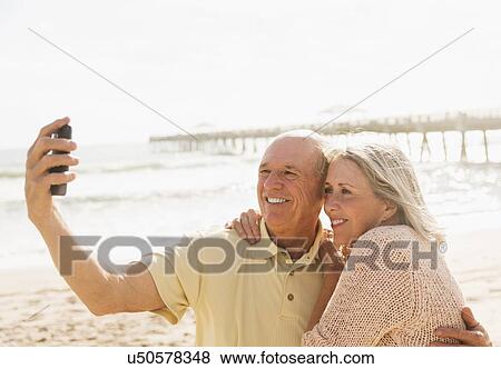 Senior couple taking picture of themselves on beach View Large Photo Image Stock Photo - Senior couple taking picture of themselves on beach. Fotosearch