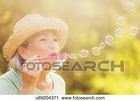 Senior woman blowing soap bubbles View Large Photo Image Stock Image - Senior woman blowing soap bubbles. Fotosearch