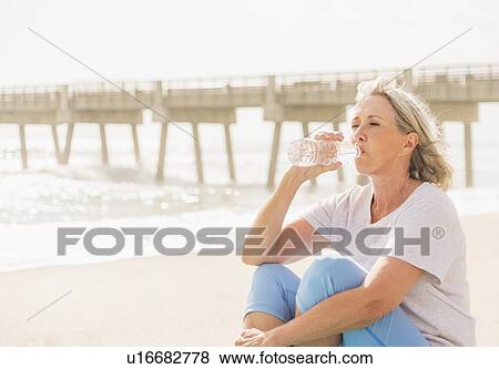 Senior woman drinking water on beach View Large Photo Image Stock Photo - Senior woman drinking water on beach. Fotosearch