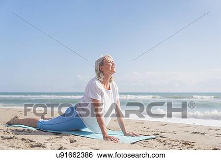 Stock Photograph - Senior woman exercising on beach. Fotosearch