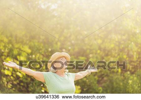 Stock Photograph - Senior woman in park with arms outstretched. Fotosearch