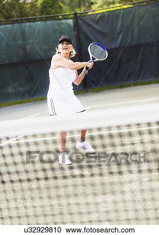 Stock Image - Senior woman playing tennis. Fotosearch