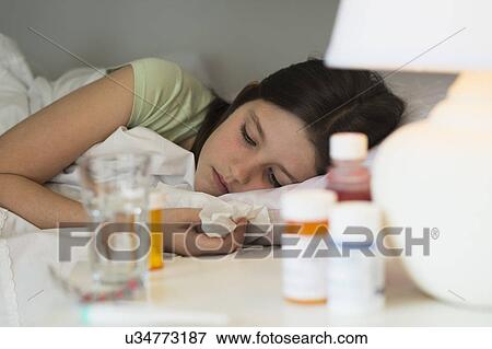Stock Photo - Sick girl (8-9) lying in bed. Fotosearch