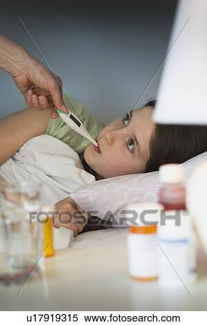 Stock Photography - Sick girl (8-9) with thermometer in mouth. Fotosearch