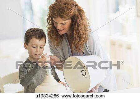 son (6-7) and mother changing lightbulb in table lamp View Large Photo Image Stock Photograph - son (6-7) and mother changing lightbulb in table lamp. Fotosearch