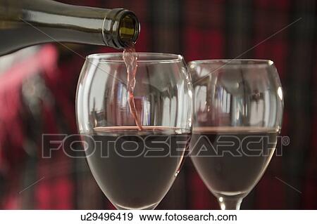 Stock Photo - Studio Shot of pouring red wine into wine glasses. Fotosearch