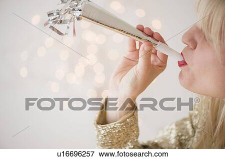 Studio Shot of woman blowing noicemaker at party View Large Photo Image Stock Photo - Studio Shot of woman blowing noicemaker at party. Fotosearch