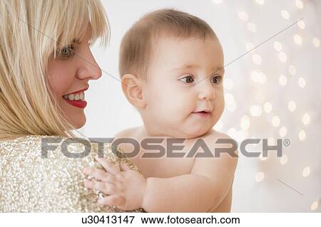 Stock Photo - Studio Shot of woman holding baby (6-11months). Fotosearch