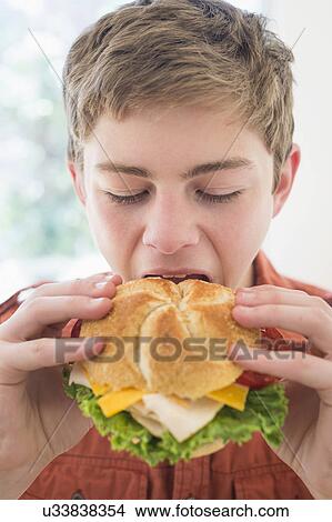 Teenage boy (16-17) eating cheese and turkey sandwich View Large Photo Image Picture - Teenage boy (16-17) eating cheese and turkey sandwich. Fotosearch