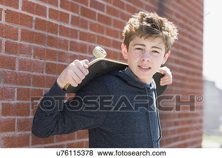Stock Photo - Teenage boy (16-17) holding skateboard. Fotosearch