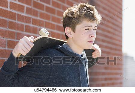 Teenage boy (16-17) holding skateboard View Large Photo Image Stock Photograph - Teenage boy (16-17) holding skateboard. Fotosearch
