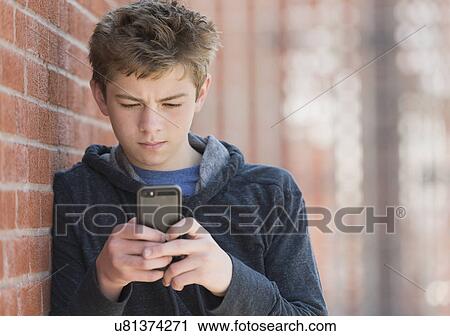 Teenage boy (16-17) leaning against brick wall texting View Large Photo Image Stock Image - Teenage boy (16-17) leaning against brick wall texting. Fotosearch