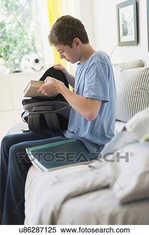 Teenage boy (16-17) packing books into backpack View Large Photo Image Stock Photography - Teenage boy (16-17) packing books into backpack. Fotosearch