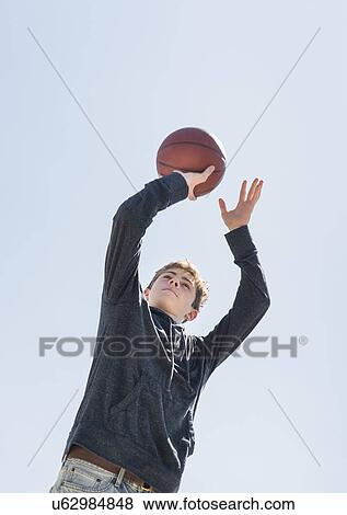 Stock Photo - Teenage boy (16-17) playing basketball. Fotosearch