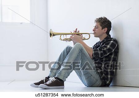 Teenage boy (16-17) playing trumpet in hallway View Large Photo Image Picture - Teenage boy (16-17) playing trumpet in hallway. Fotosearch