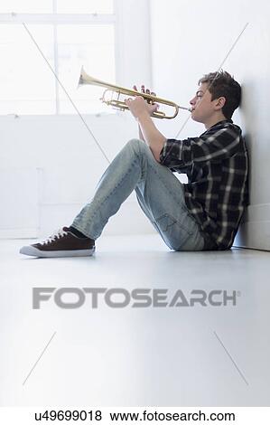 Teenage boy (16-17) playing trumpet in hallway View Large Photo Image Stock Photo - Teenage boy (16-17) playing trumpet in hallway. Fotosearch