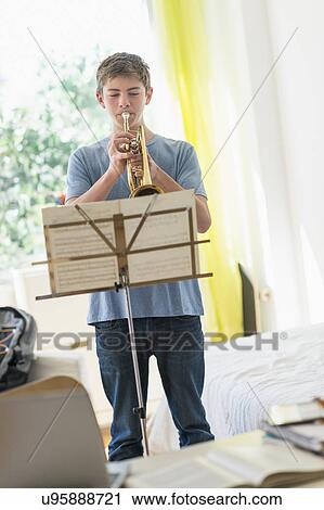 Stock Image - Teenage boy (16-17) playing trumpet. Fotosearch