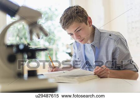 Teenage boy (16-17) reading book in laboratory View Large Photo Image Stock Photography - Teenage boy (16-17) reading book in laboratory. Fotosearch