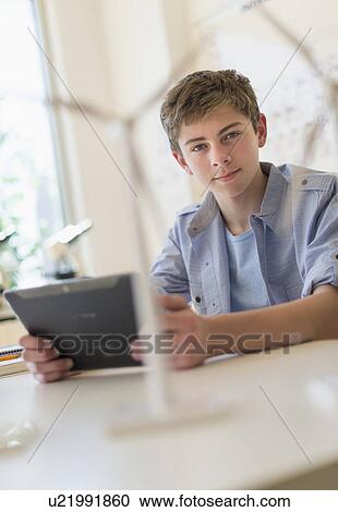 Stock Image - Teenage boy (16-17) using digital tablet in laboratory. Fotosearch