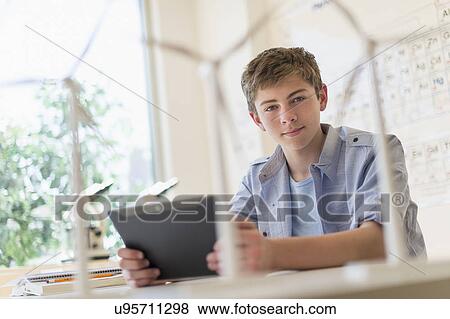 Stock Photo - Teenage boy (16-17) using digital tablet in laboratory. Fotosearch