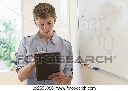 Teenage boy (16-17) using digital tablet in classroom View Large Photo Image Stock Photograph - Teenage boy (16-17) using digital tablet in classroom. Fotosearch