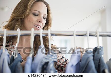 Picture - Woman choosing clothes from rack. Fotosearch