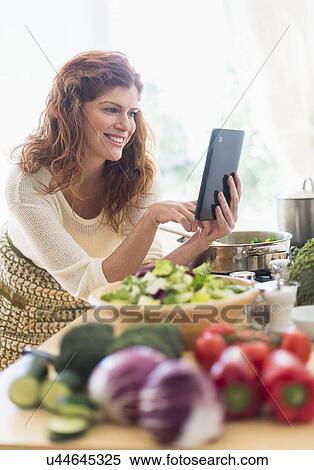 Woman cooking and using digital tablet in kitchen View Large Photo Image Stock Photography - Woman cooking and using digital tablet in kitchen. Fotosearch