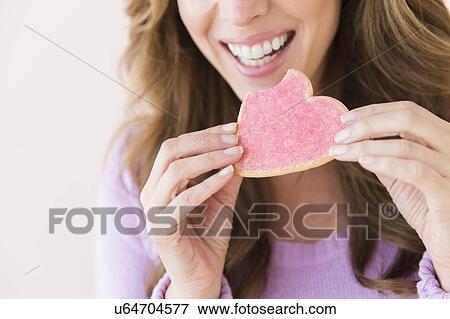 Stock Photo - Woman holding heart shape cookie. Fotosearch
