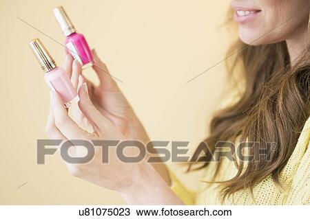Stock Image - Woman holding nail polish. Fotosearch