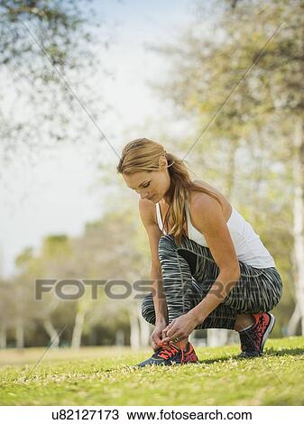 Woman in park tying shoe View Large Photo Image Stock Image - Woman in park tying shoe. Fotosearch