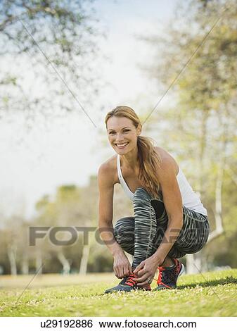 Stock Photograph - Woman in park tying shoe. Fotosearch