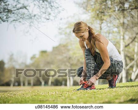 Stock Photograph - Woman in park tying shoe. Fotosearch