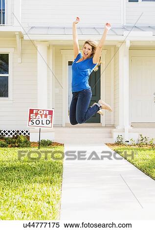 Stock Photography - Woman jumping in front of new house. Fotosearch