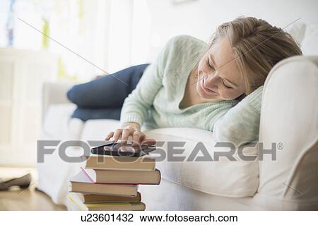 Woman lying on sofa and using digital tablet View Large Photo Image Stock Image - Woman lying on sofa and using digital tablet. Fotosearch