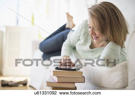 Woman lying on sofa and using digital tablet View Large Photo Image Stock Image - Woman lying on sofa and using digital tablet. Fotosearch
