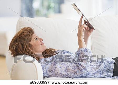 Woman lying on sofa and using laptop View Large Photo Image Stock Photo - Woman lying on sofa and using laptop. Fotosearch