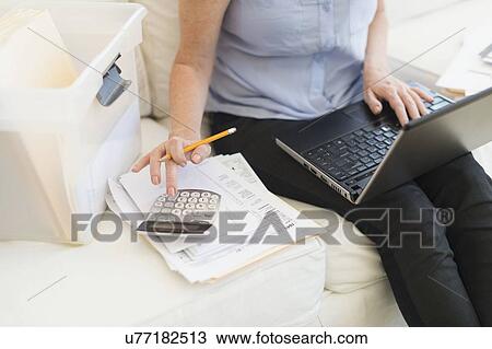 Stock Image - Woman paying bills via internet. Fotosearch