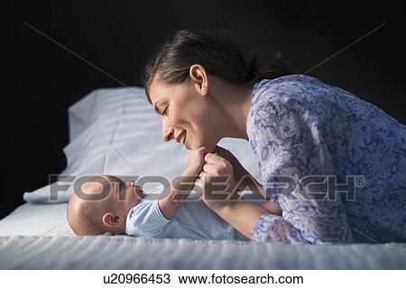 Stock Image - Woman playing with baby boy (2-5 months). Fotosearch