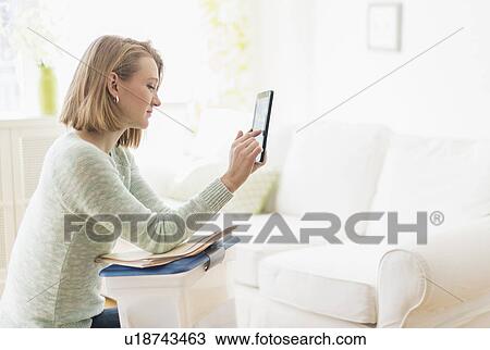 Woman sitting in living room and using digital tablet View Large Photo Image Stock Image - Woman sitting in living room and using digital tablet. Fotosearch