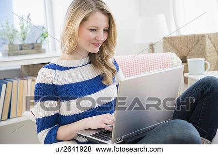 Woman sitting on sofa and using laptop View Large Photo Image Stock Photo - Woman sitting on sofa and using laptop. Fotosearch