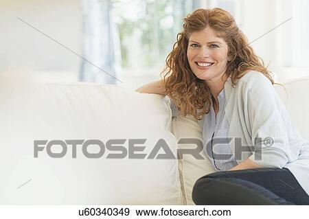 Woman sitting on sofa View Large Photo Image Stock Photo - Woman sitting on sofa. Fotosearch