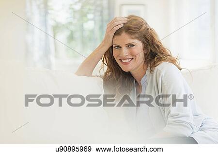 Stock Photo - Woman sitting on sofa. Fotosearch