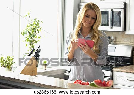 Woman text messaging in kitchen View Large Photo Image Stock Photograph - Woman text messaging in kitchen. Fotosearch