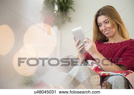 Stock Image - Woman using digital tablet at christmas time. Fotosearch