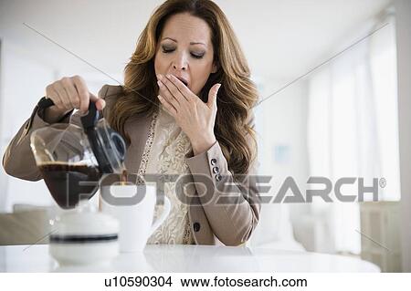 Yawnging woman pouring coffee View Large Photo Image Picture - Yawnging woman pouring coffee. Fotosearch